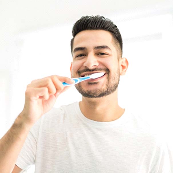 Man preventing dental emergencies in Bakersfield by brushing teeth