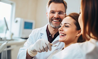 Dentist smiling with patient and dental assistant