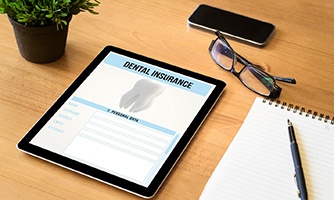 Dental insurance form on tablet next to notepad, glasses, and plant
