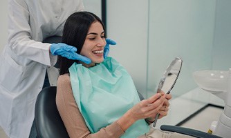 Woman smiling at reflection in handheld mirror