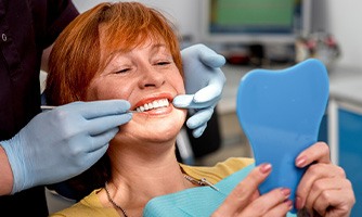 Red-haired woman in dental chair with dentist touching her teeth