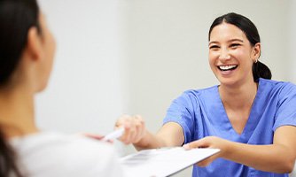 A woman paying a dentist for treatment