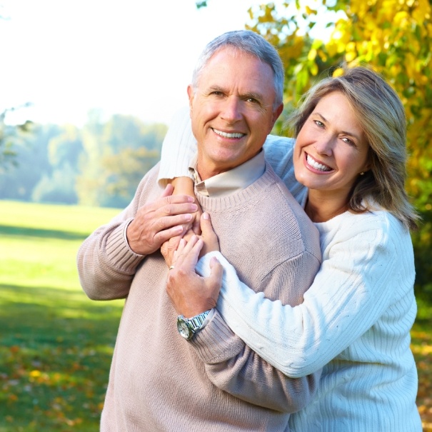 Man and woman with healthy smiles after dental implant tooth replacement