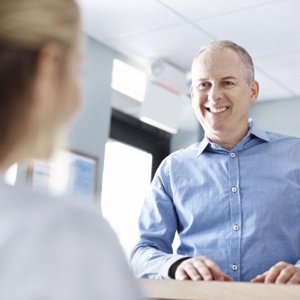 Man checking in at dental office reception desk