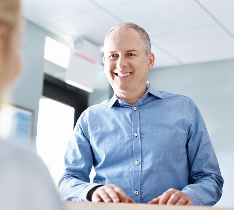 Man handing in dental insurance forms at dental office