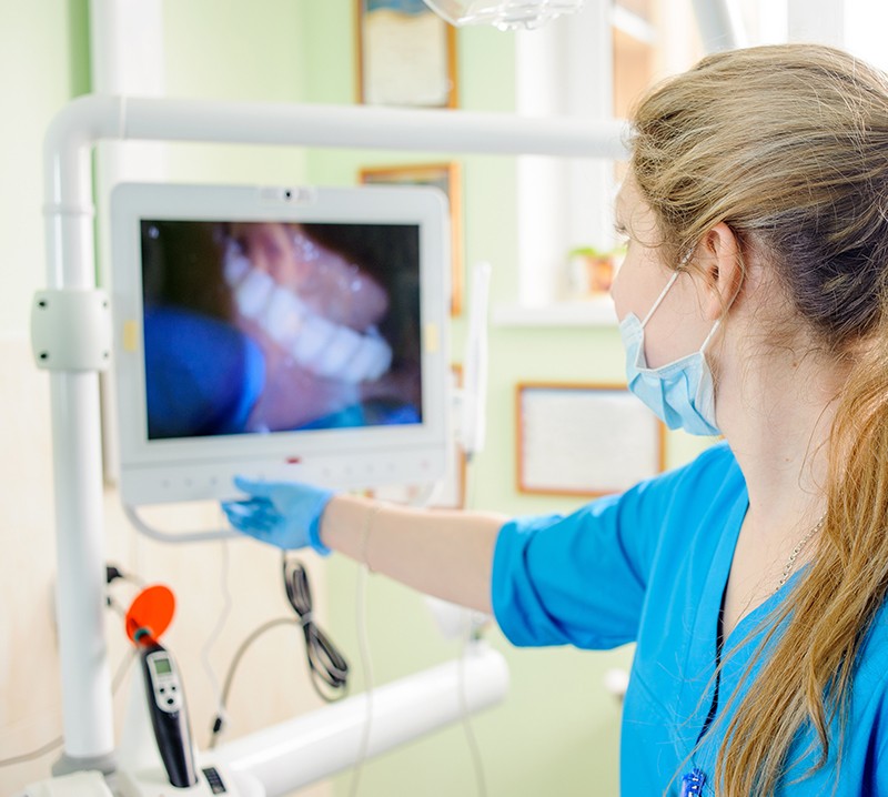 Dental team member looking at digital images on chairside computer screen