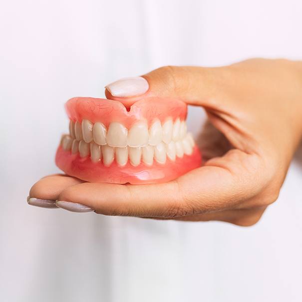 Hand holding a full set of dentures