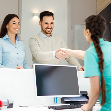 Man and woman discussing dental insurance with dental team member