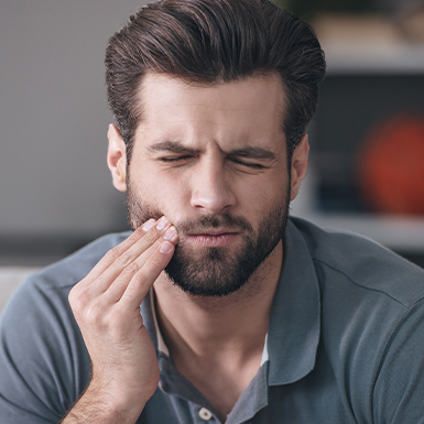 Man in need of emergency dentistry holding jaw in pain