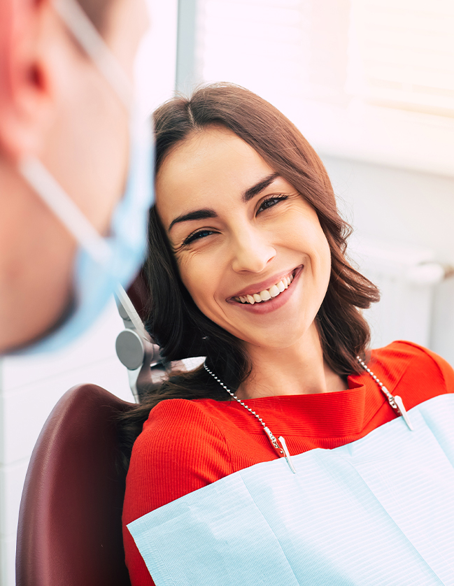 Woman in dental chair laughing with her dentist