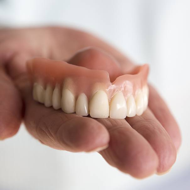 Hand holding a full denture