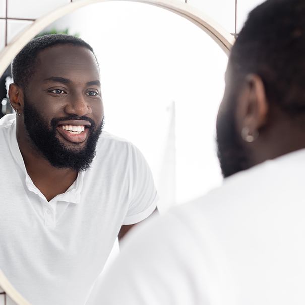 Man looking at his bright smile after teeth whitening