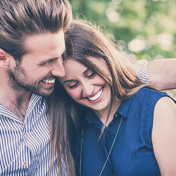 Man and woman smiling after porcelain veneer treatment