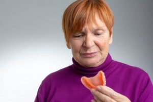 Woman with denture sores looking at her dentures